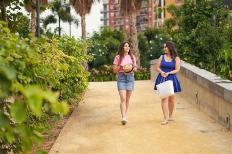 Premium Photo Two Friends Talking While Walking In The Park