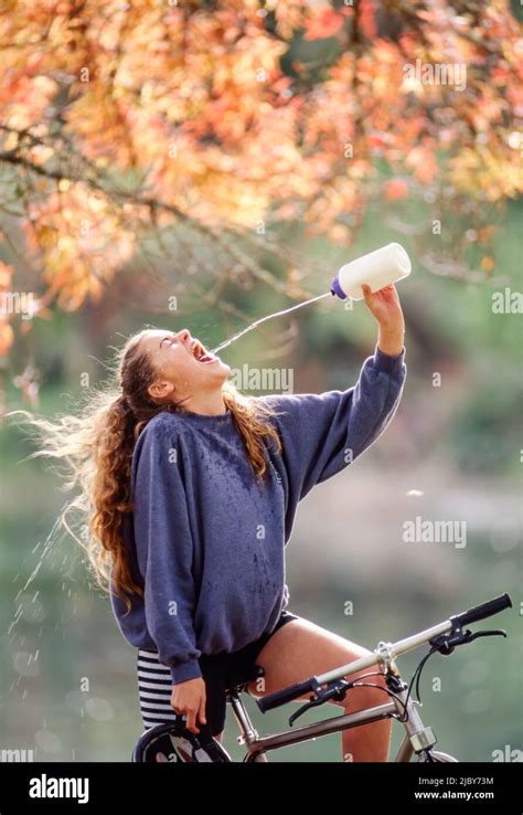 Young Woman Stopped On Her Bicycle Squirting Water Into Her Mouth From