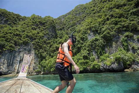 an active man on thai traditional longtail boat is ready to snorkel and dive phi phi islands