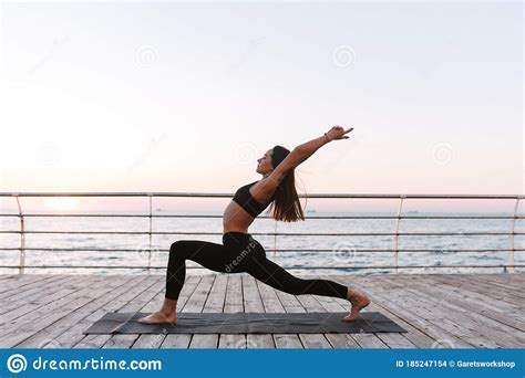 Beautiful Young Lady Standing And Training Yoga Poses By The Sea Stock