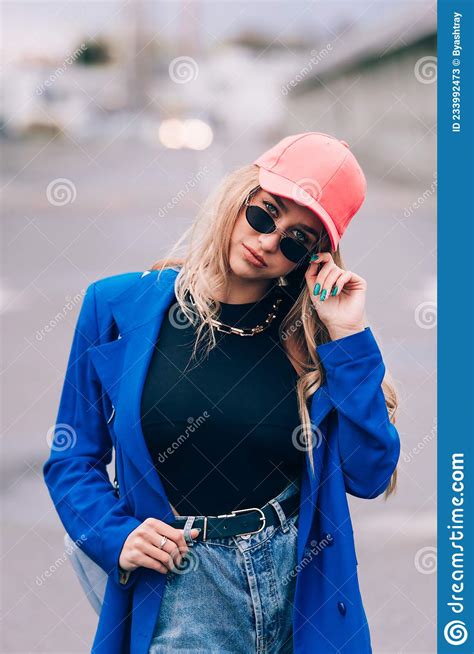 Young Blonde Hipster Woman Posing On The Street Wearing Blue Stylish Jacket Jeans And Baseball