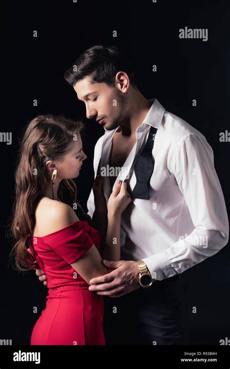 Woman In Red Dress Undressing Man Shirt Isolated On Black Stock Photo