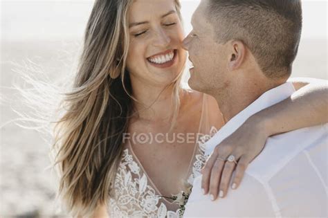 Happy Affectionate Bride And Groom Hugging Outdoors — Windswept