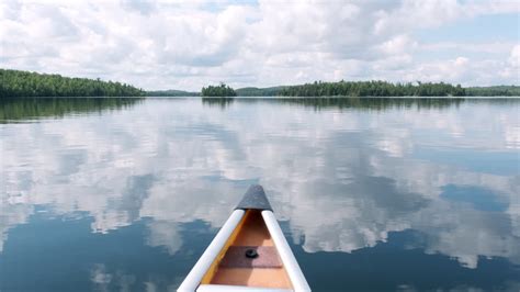 Premium Stock Video Glassy Lake Canoe Pov With Sky Reflection