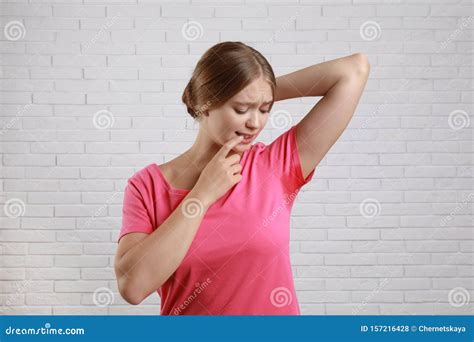Young Woman With Sweat Stain On Her Clothes Brick Wall Using Deodorant