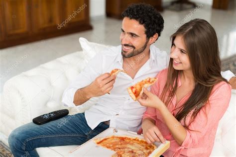 Couple regarder la télévision et manger de la pizza image libre de