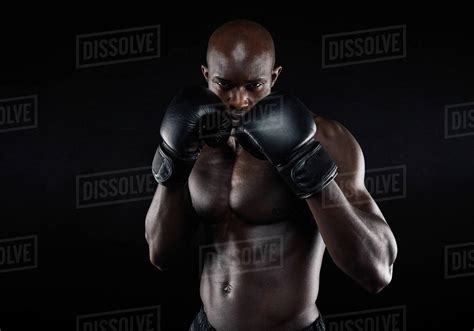 Portrait Of Tough Male Boxer Posing In Boxing Stance Against Black