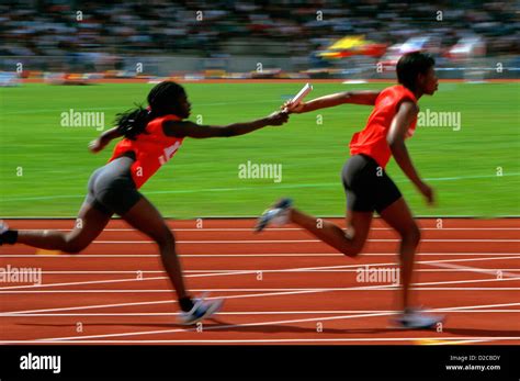Track And Field Runners In A Relay Race Passing Baton Stock Photo
