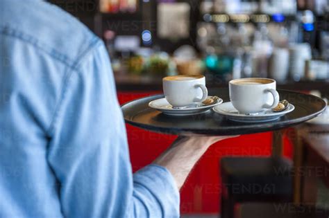 Waiter Carrying Tray With Cappuccino Cups In A Cafe Stock Photo
