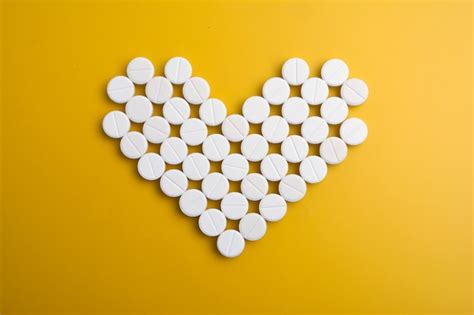 Premium Photo Pills In Shape Of Heart On Yellow Background Flat Lay