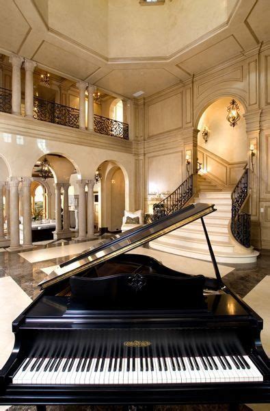 Sitting room with bookshelf, books, arm chair, sofa and fireplace. Stunning grand piano in the hallway of a luxury home ...