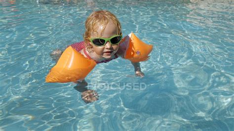 Маленькая девочка с водными крыльями в бассейне — содержание Вода