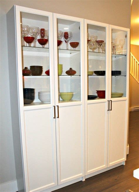 A White Cabinet With Glass Doors And Dishes On Its Shelves In A Living