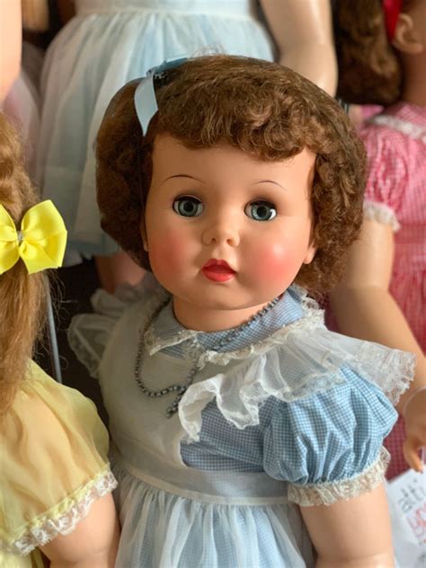 Two Dolls Are Standing Next To Each Other In Front Of Many Other Dolls