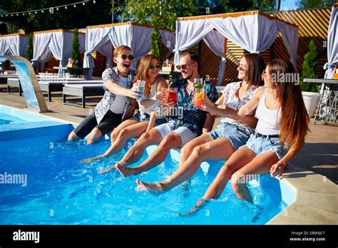 Group Of Friends Having Fun At Poolside Party Clinking Glasses With