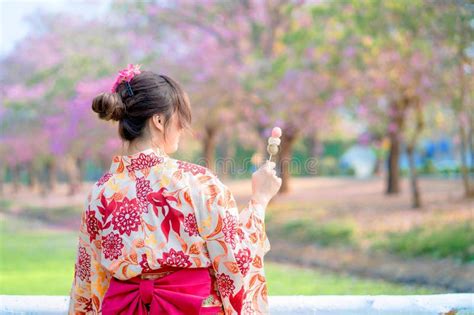 Back Of Japanese Woman In Traditional Kimono Dress Enjoy Travel And Holding Dango At Bridge In