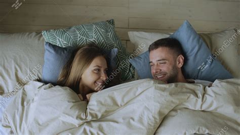 Top View Of Smiling Couple Having Fun In Bed Hiding Under Blanket And Looking Stock Video