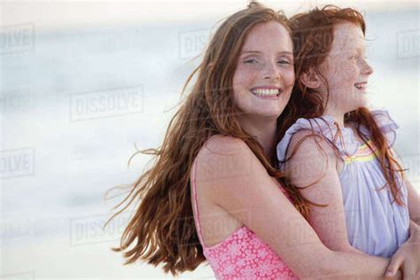 Portrait Of Mother And Daughter Smiling At Camera Embracing On Sunny