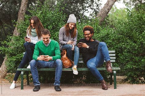 group of friends hanging out chatting with their smartphones by stocksy contributor