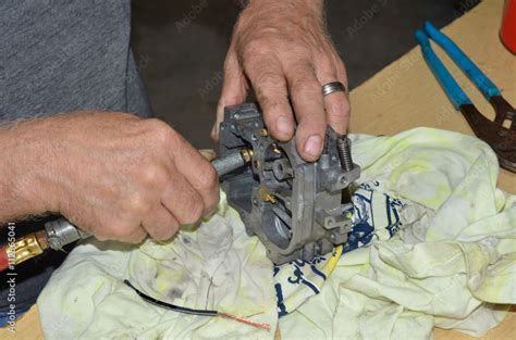 Mechanic working on rebuilding a carburetor. His hands are shown using