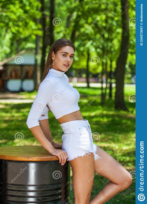 Portrait Of A Young Beautiful Brunette Woman In White Denim Shorts