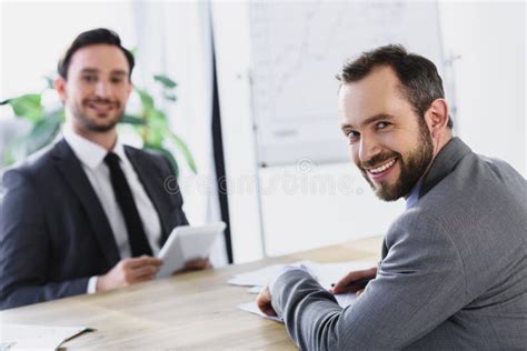 Smiling Businessmen Sitting At Table During Meeting Stock Photo Image