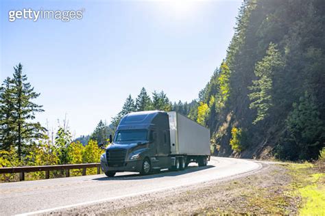 Stylish Dark Gray Big Rig Semi Truck Transporting Cargo In Dry Van Semi