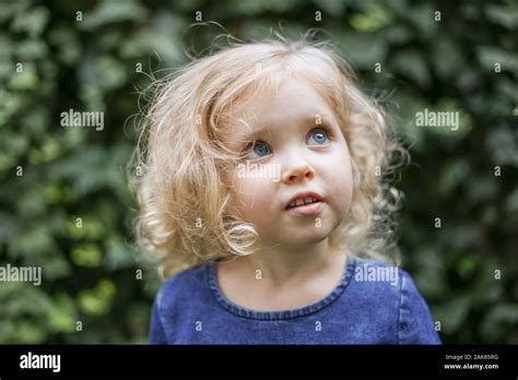 Portrait Of A Little Beautiful European Girl With Curly Blonde Hair And Blue Eyes Of 3 To 4