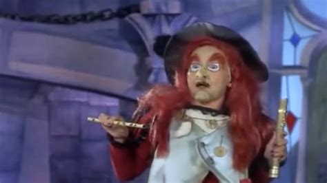 An Image Of A Man In Costume With Red Hair And Makeup Holding A Golden