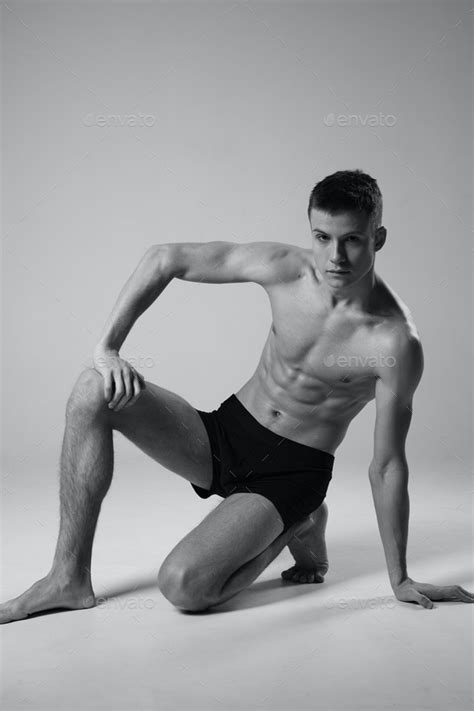 Athlete Sitting On The Floor Indoors In Shorts And Naked Torso Black