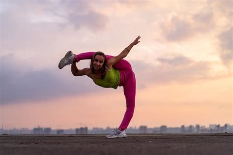 premium photo flexible woman doing split outdoor on the dramatic sunset background concept of