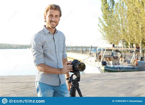 Young Male Photographer Standing With Professional Camera At Pier