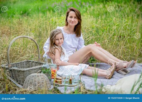 Beautiful Young Mother And Her Little Daughter In White Dress Having Fun In A Picnic They Are