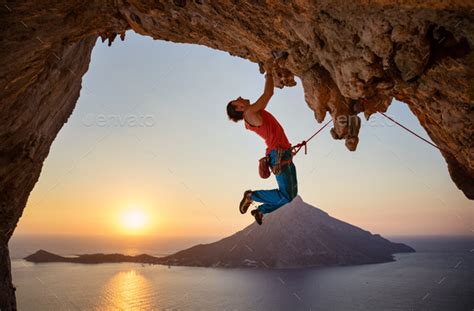 Male Rock Climber Hanging With One Hand On Challenging Route Stock