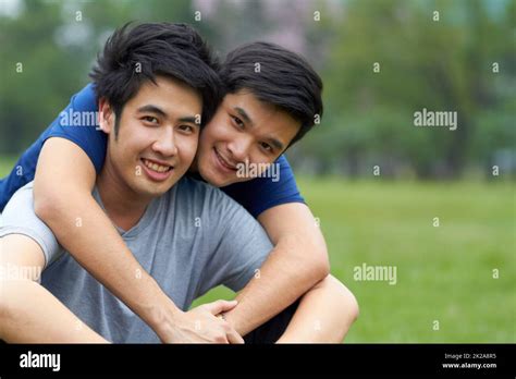 Living And Loving Together Cute Young Gay Asian Couple Smiling Together While Sitting In The