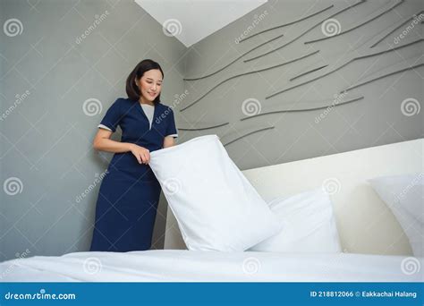 empregada asiática criada no quarto de uma jovem que faz o travesseiro da cama no hotel foto