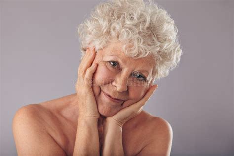 Portrait Of Beautiful Naked Senior Woman Looking Happy Against Grey