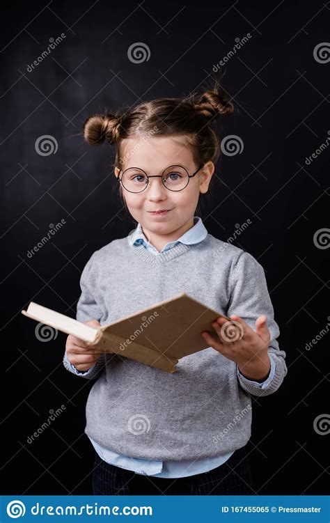 Adorable Elementary Schoolgirl In Eyeglasses Reading Book In Front Of