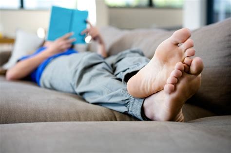 Premium Photo Woman Lying Barefoot On The Couch Reading A Book