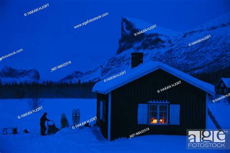 A Mountain Cabin With Lights On In The Window Stock Photo Picture And
