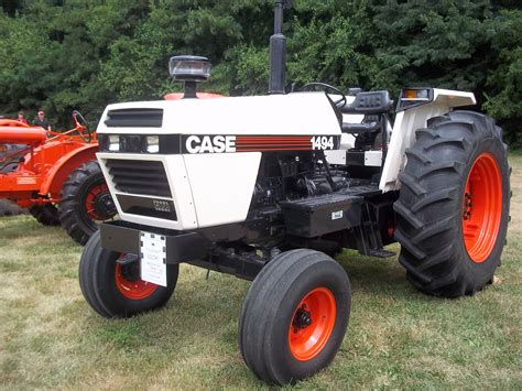 An Orange And White Tractor Is Parked In The Grass