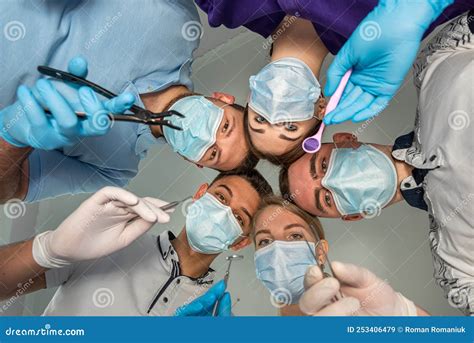 A Cheerful Group Of Dentists And Their Assistants Stand In The Dental Office And Smile Happily