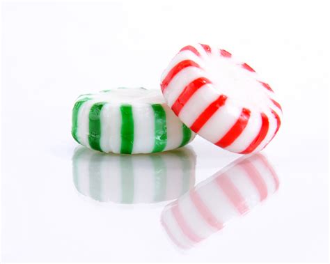 Red And Green Peppermint Candies On A Reflective White Background