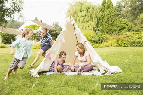 Father Chasing Son Around Teepee In Backyard — Outdoors Playful