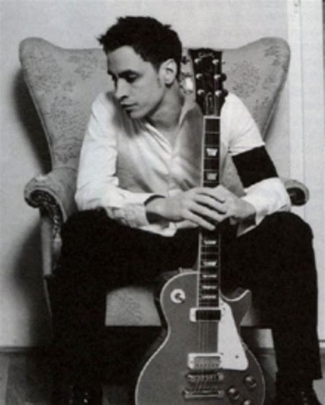 A Man Sitting In A Chair Holding An Electric Guitar