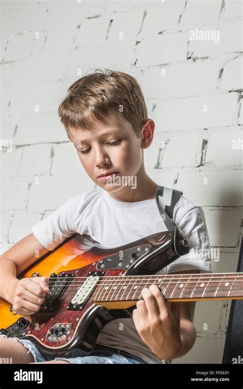 Boy Playing Guitar Against Wall At Home Stock Photo Alamy
