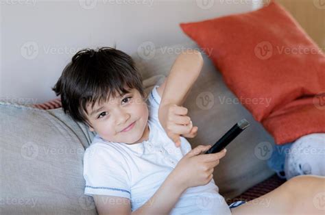 Young Boy Holding Remote Control And Looking At Camera With Smiling