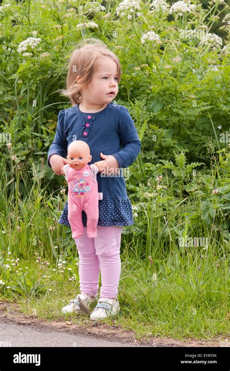 Little Girl Standing Holding Her Doll Stock Photo Alamy