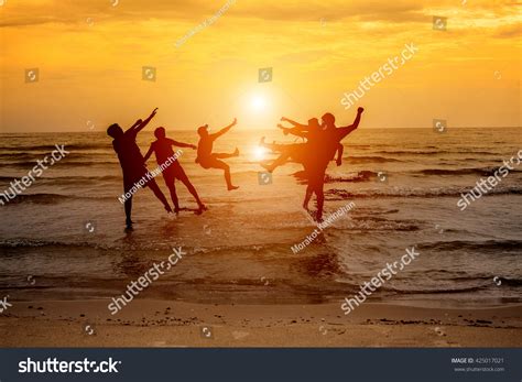 Group Of Happy People Jumping In The Sea At Sunset Concept About