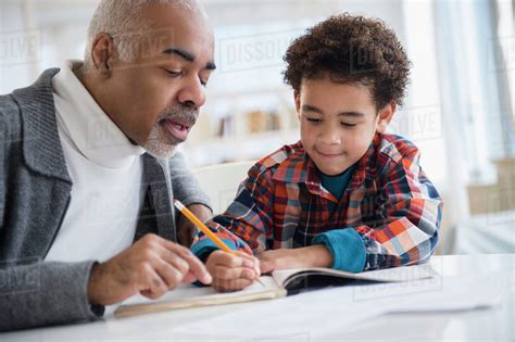 Mixed Race Grandfather Helping Grandson Do Homework Stock Photo